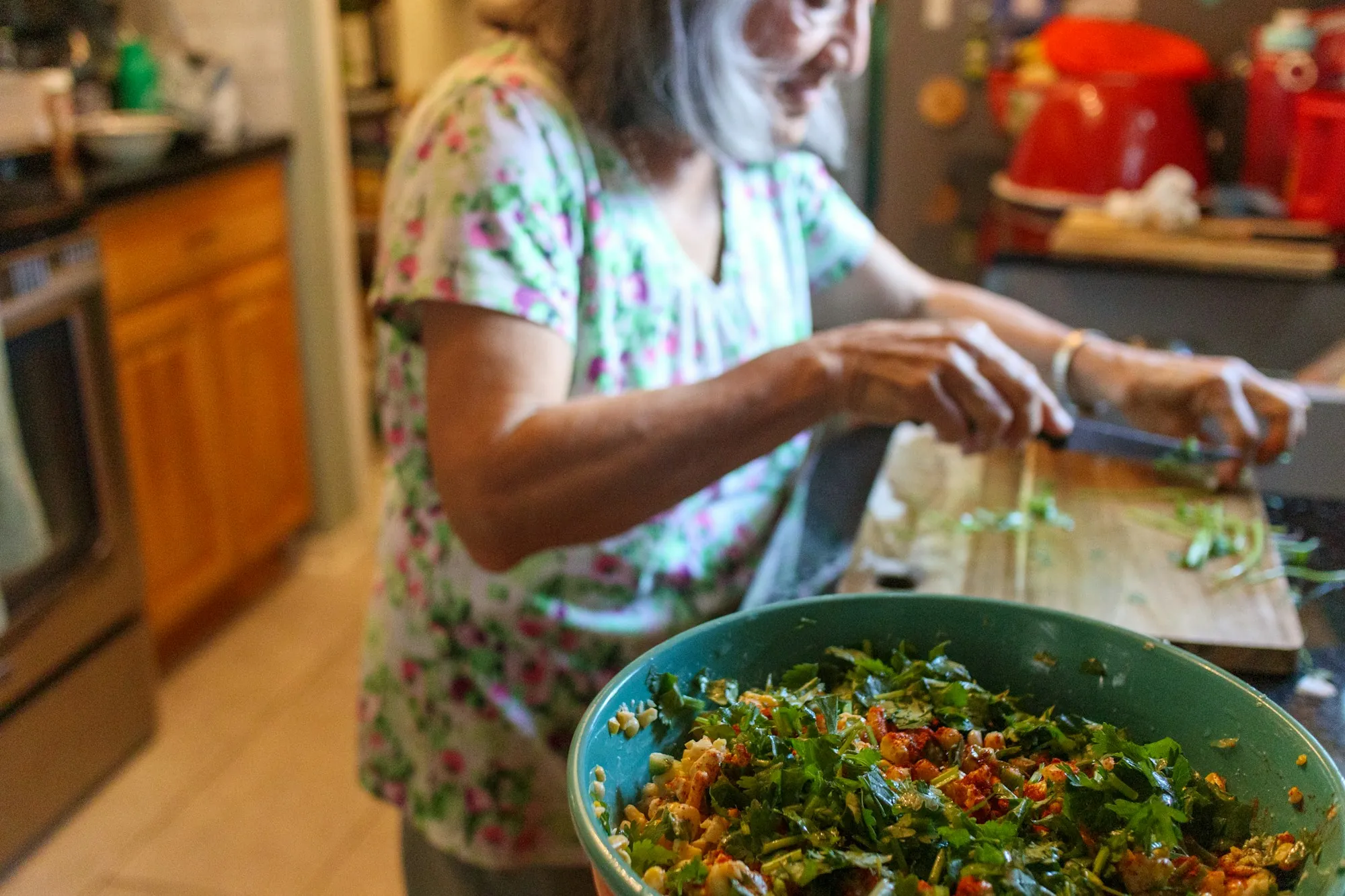 A woman chopping salad vegetables at a kitchen counter